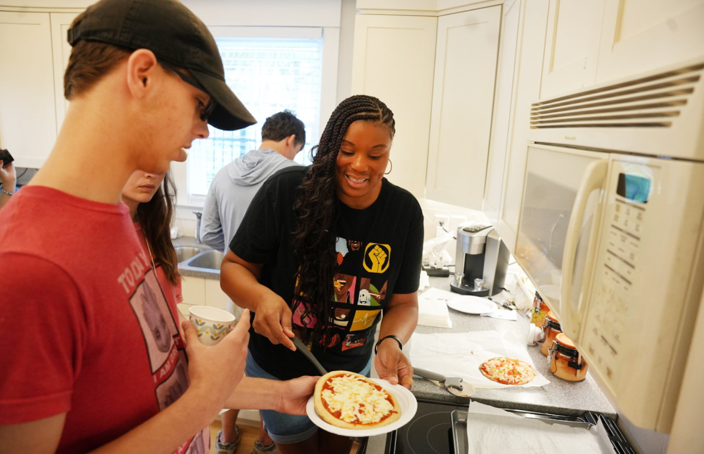 Sherri Burrell assists EXCEL student cooking pizza at the AWARE Home.